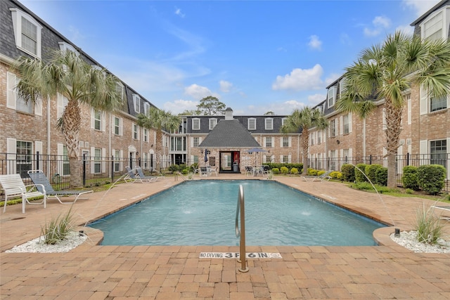 community pool featuring a patio area, fence, and a residential view