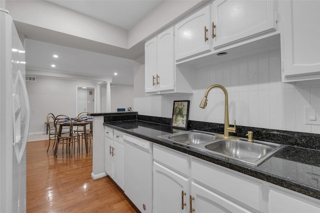 kitchen with light wood-type flooring, a sink, white cabinets, ornate columns, and white appliances