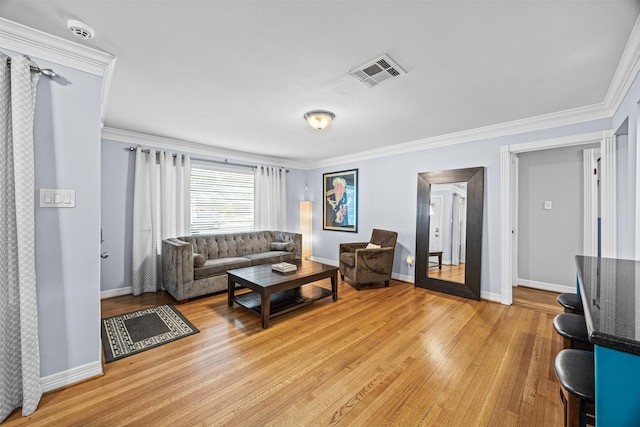 living area featuring baseboards, ornamental molding, light wood-type flooring, and visible vents