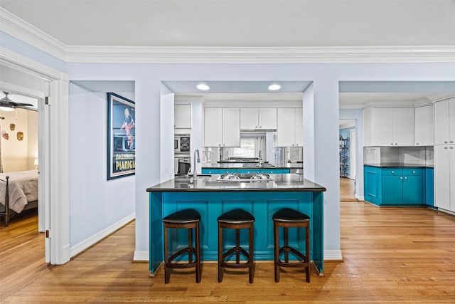 kitchen with crown molding, dark countertops, white cabinets, and a breakfast bar area