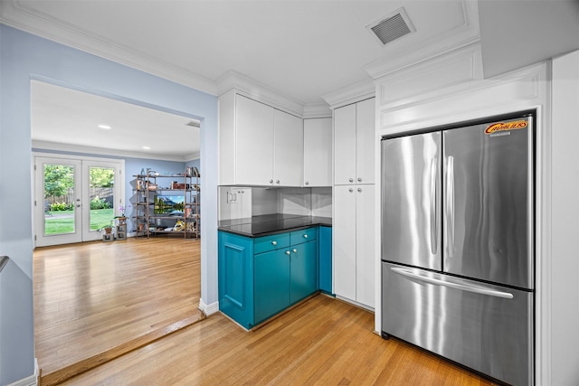 kitchen featuring white cabinets, dark countertops, light wood-style flooring, freestanding refrigerator, and visible vents