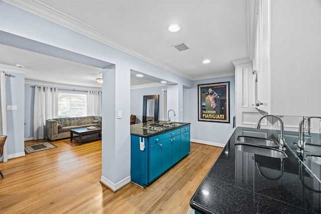 kitchen with blue cabinetry, visible vents, dark countertops, ornamental molding, and light wood-style flooring