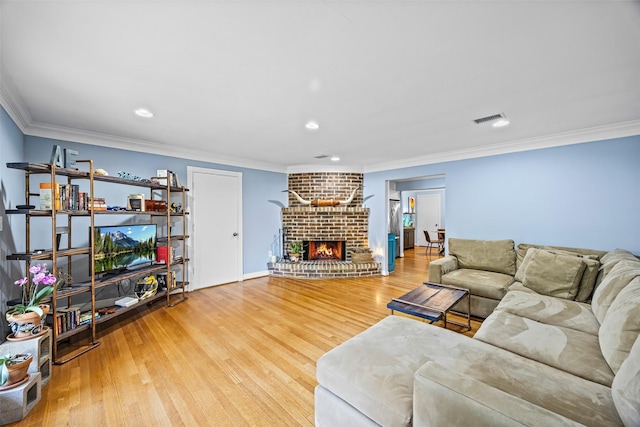 living room with crown molding, a brick fireplace, recessed lighting, wood finished floors, and visible vents