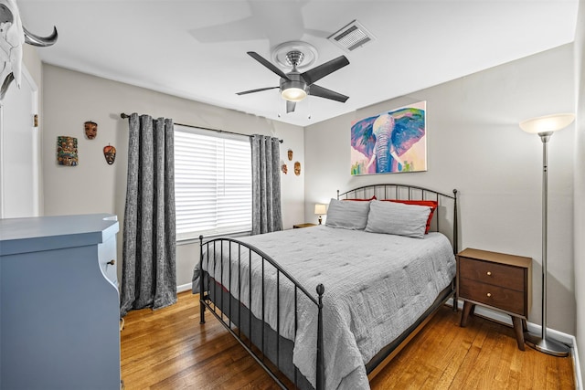 bedroom featuring visible vents, a ceiling fan, baseboards, and hardwood / wood-style flooring