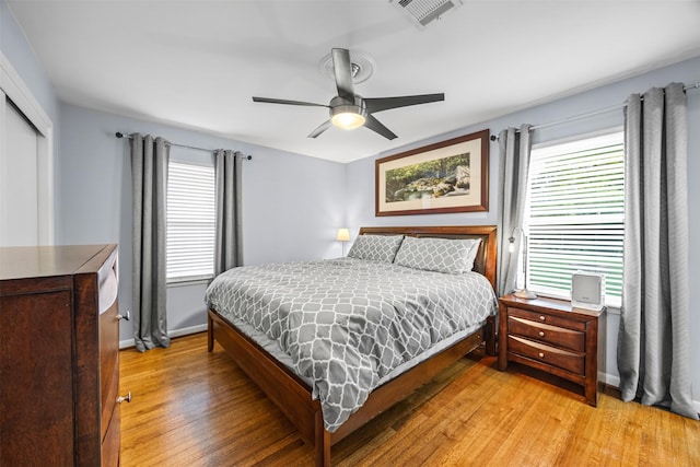 bedroom with visible vents, multiple windows, light wood finished floors, and a closet