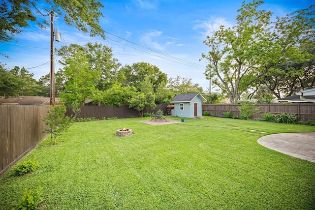 view of yard with a fire pit, a patio, a fenced backyard, a shed, and an outbuilding