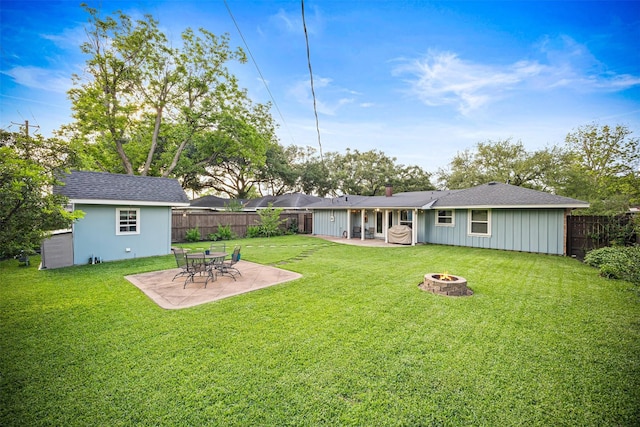 rear view of house with a fenced backyard, a yard, a fire pit, and a patio area