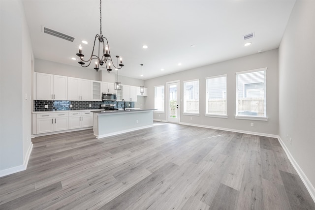 kitchen with white cabinets, appliances with stainless steel finishes, an inviting chandelier, tasteful backsplash, and visible vents