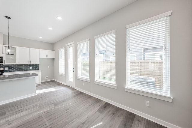 kitchen featuring baseboards, white cabinetry, light wood finished floors, and hanging light fixtures