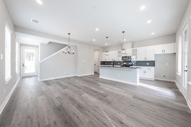 kitchen with appliances with stainless steel finishes, tasteful backsplash, open floor plan, and a chandelier