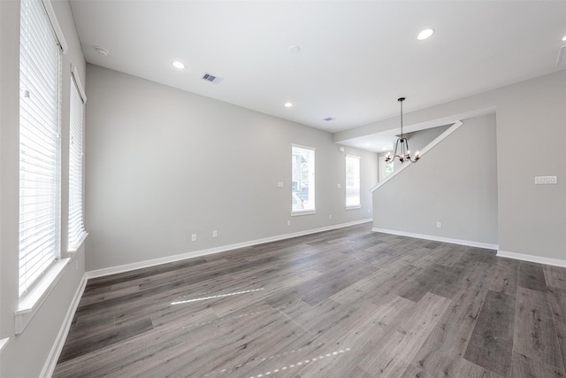 spare room with wood finished floors, recessed lighting, a chandelier, and visible vents