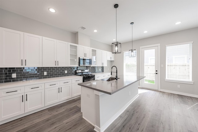 kitchen with decorative backsplash, light wood-type flooring, a sink, stainless steel microwave, and gas range oven