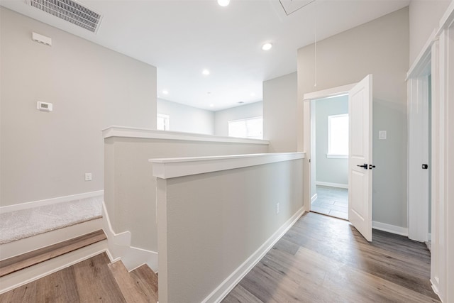 hall with attic access, visible vents, wood finished floors, baseboards, and recessed lighting