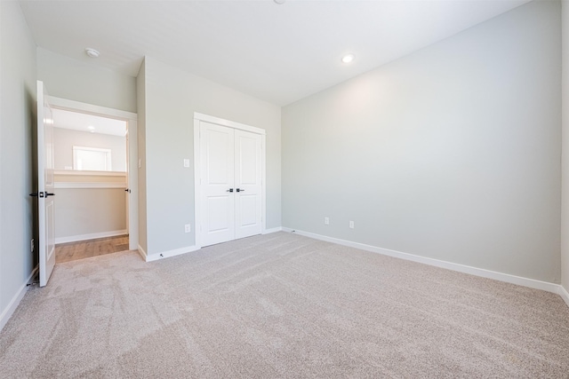 unfurnished bedroom featuring baseboards, a closet, recessed lighting, and light colored carpet