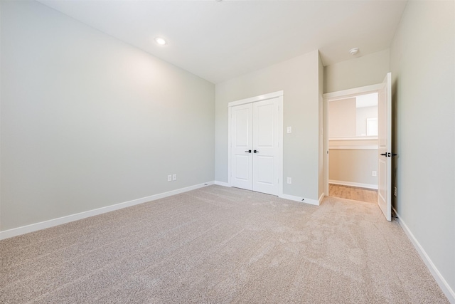 unfurnished bedroom featuring baseboards, a closet, recessed lighting, and light colored carpet