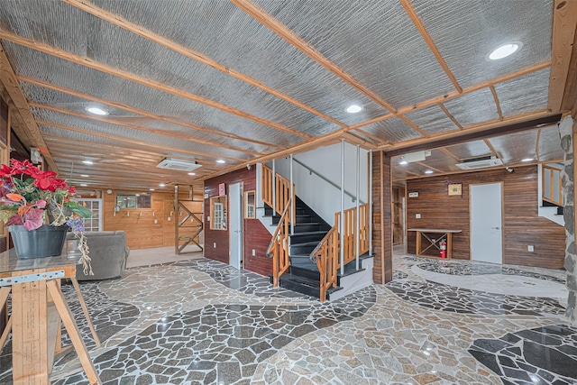 misc room with stone flooring, wood walls, recessed lighting, visible vents, and stairway