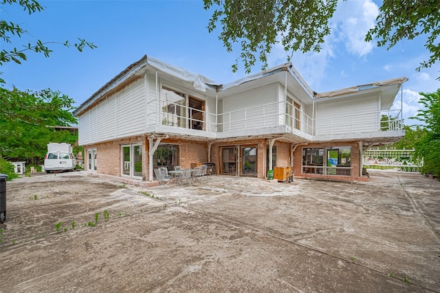 back of property with brick siding, a balcony, and a patio