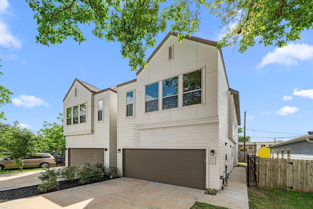 view of front of home with an attached garage, fence, and driveway