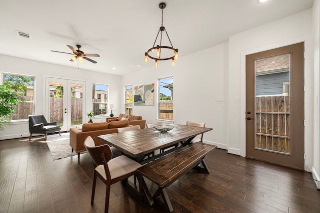 dining space featuring visible vents, a wealth of natural light, ceiling fan with notable chandelier, and dark wood-type flooring