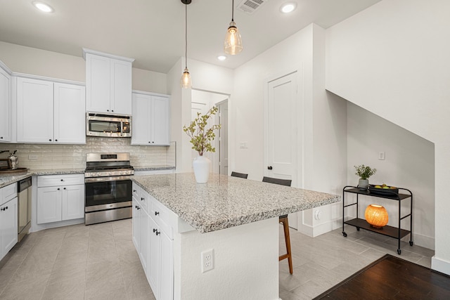 kitchen with visible vents, decorative backsplash, light stone countertops, a center island, and stainless steel appliances
