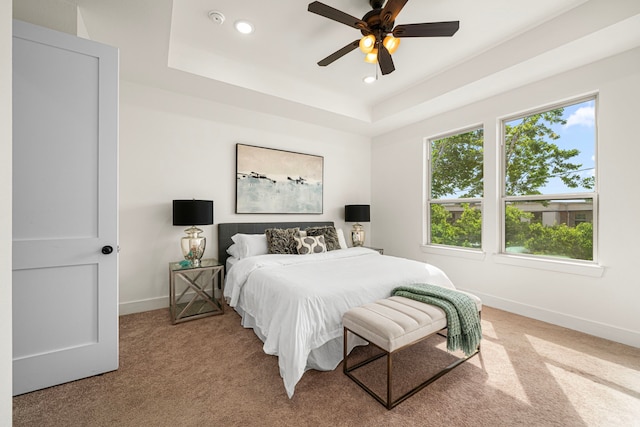 bedroom with light carpet, a raised ceiling, recessed lighting, baseboards, and a ceiling fan