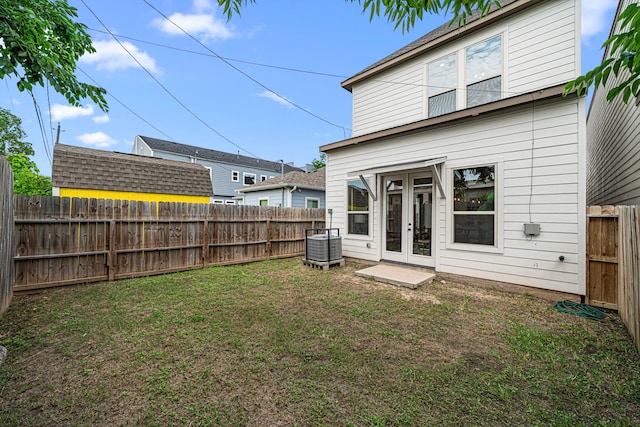 back of house with french doors, a lawn, and a fenced backyard