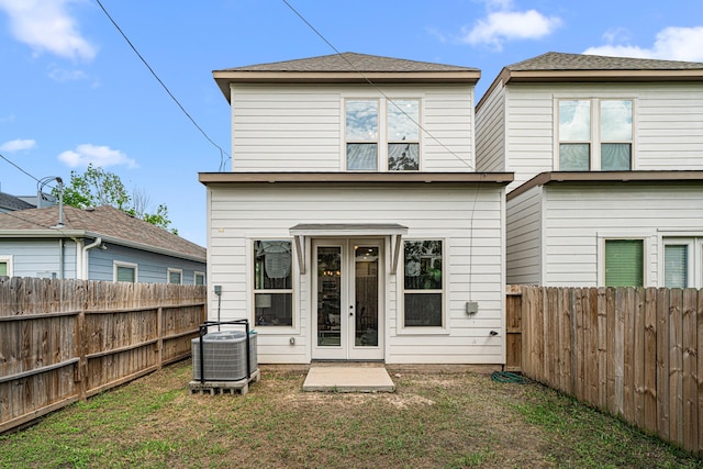 rear view of property featuring a yard, central AC, french doors, and a fenced backyard