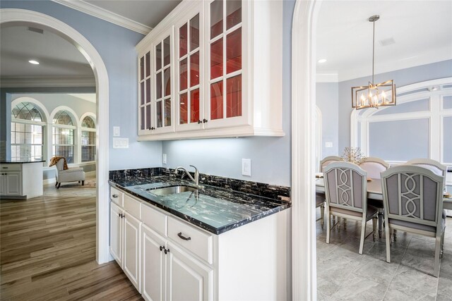 16122 Wimbledon Forest Dr, Spring, TX 77379 - kitchen with a sink, crown molding, arched walkways, a chandelier, and glass insert cabinets
