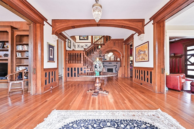 entrance foyer featuring arched walkways, wood finished floors, a fireplace, and stairway
