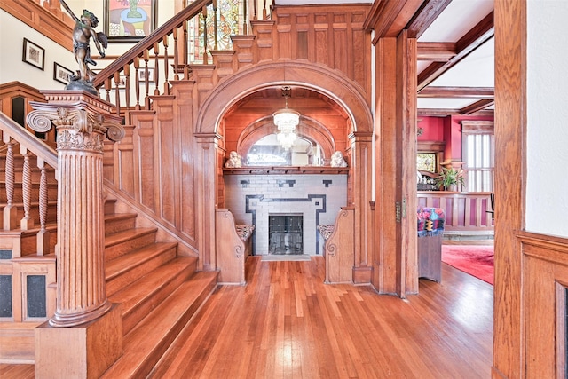 foyer featuring beam ceiling, a fireplace, a decorative wall, hardwood / wood-style floors, and stairway