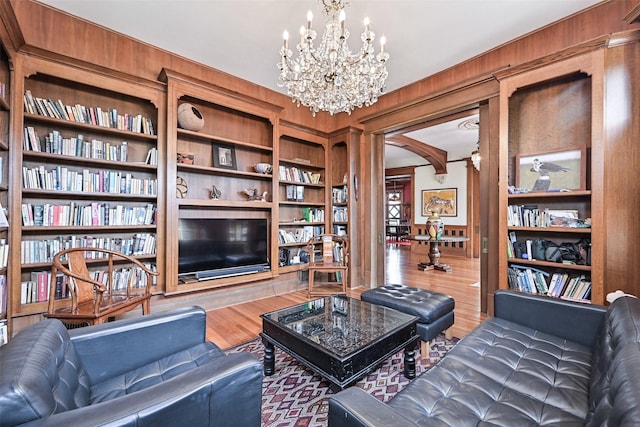 living room featuring an inviting chandelier, arched walkways, built in features, and wood finished floors