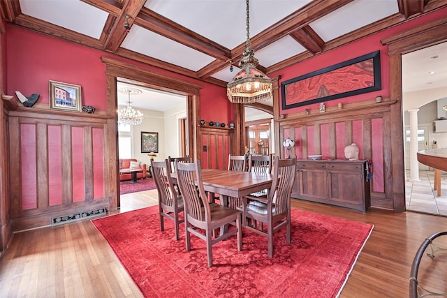 dining room with plenty of natural light, decorative columns, wood finished floors, and a chandelier