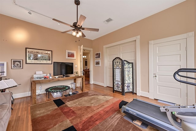 exercise area with baseboards, a ceiling fan, wood finished floors, and visible vents