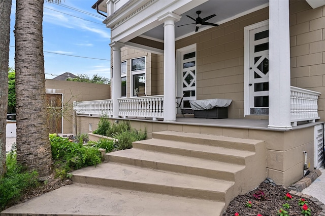 doorway to property with covered porch, fence, and a ceiling fan