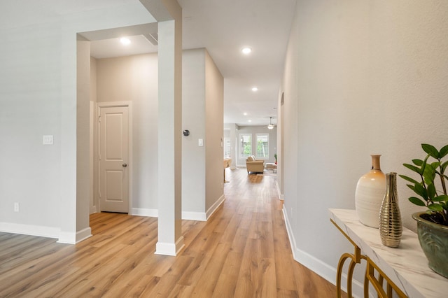 corridor featuring baseboards, recessed lighting, and light wood-style flooring