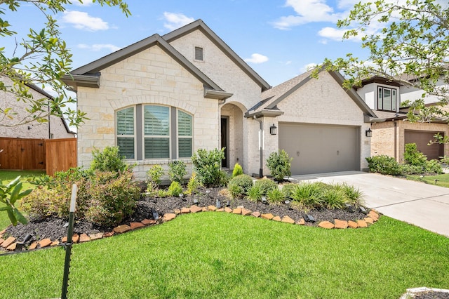 french country style house with a front yard, a garage, fence, concrete driveway, and stone siding