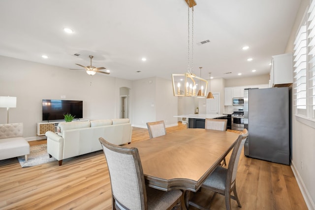 dining space with visible vents, baseboards, recessed lighting, arched walkways, and light wood-style flooring
