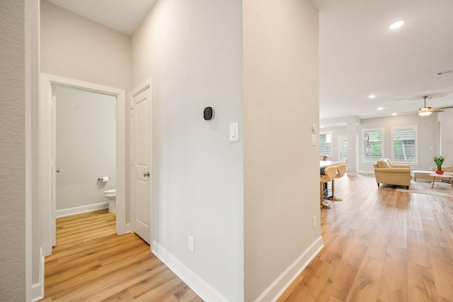corridor featuring light wood-style floors, recessed lighting, and baseboards