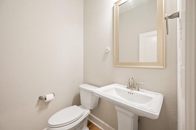 bathroom with baseboards, a sink, wood finished floors, and toilet