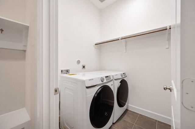 laundry room featuring dark tile patterned flooring, baseboards, laundry area, and washing machine and clothes dryer