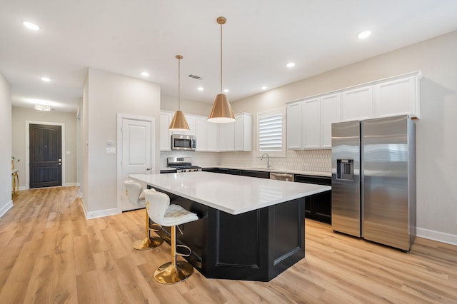 kitchen with a center island, light wood finished floors, appliances with stainless steel finishes, and visible vents