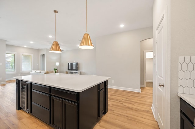 kitchen featuring light countertops, arched walkways, and light wood-style flooring