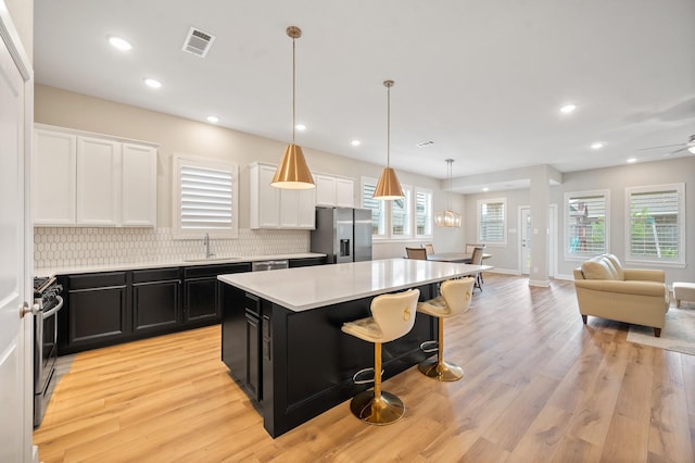 kitchen featuring a sink, dark cabinets, stainless steel appliances, open floor plan, and visible vents