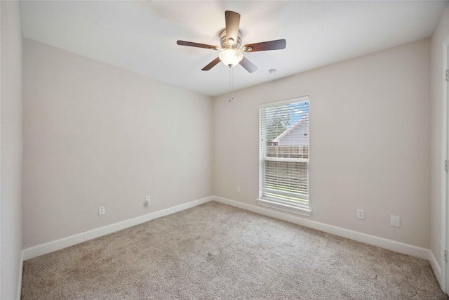 carpeted spare room featuring baseboards and a ceiling fan