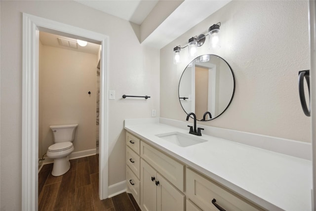 bathroom featuring visible vents, wood finished floors, vanity, baseboards, and toilet