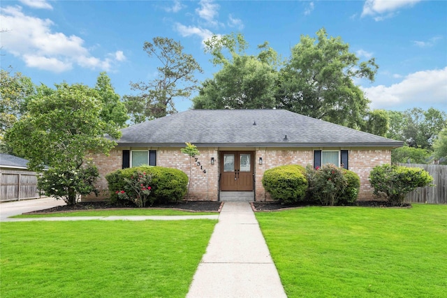 ranch-style house featuring brick siding, roof with shingles, fence, and a front yard
