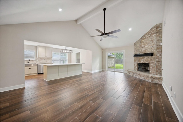 unfurnished living room with a sink, ceiling fan, beamed ceiling, and dark wood-style floors