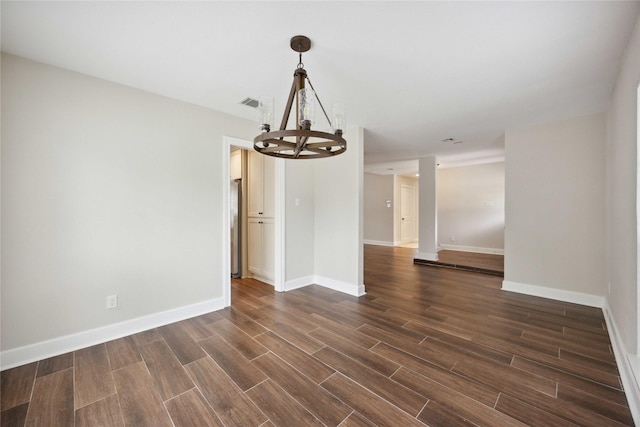unfurnished dining area featuring an inviting chandelier, baseboards, dark wood-style floors, and visible vents