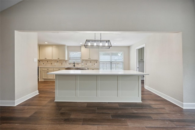 kitchen featuring light countertops, baseboards, dark wood-type flooring, backsplash, and a kitchen island