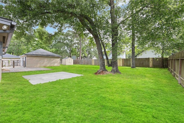 view of yard with a patio, a fenced backyard, a shed, and an outbuilding